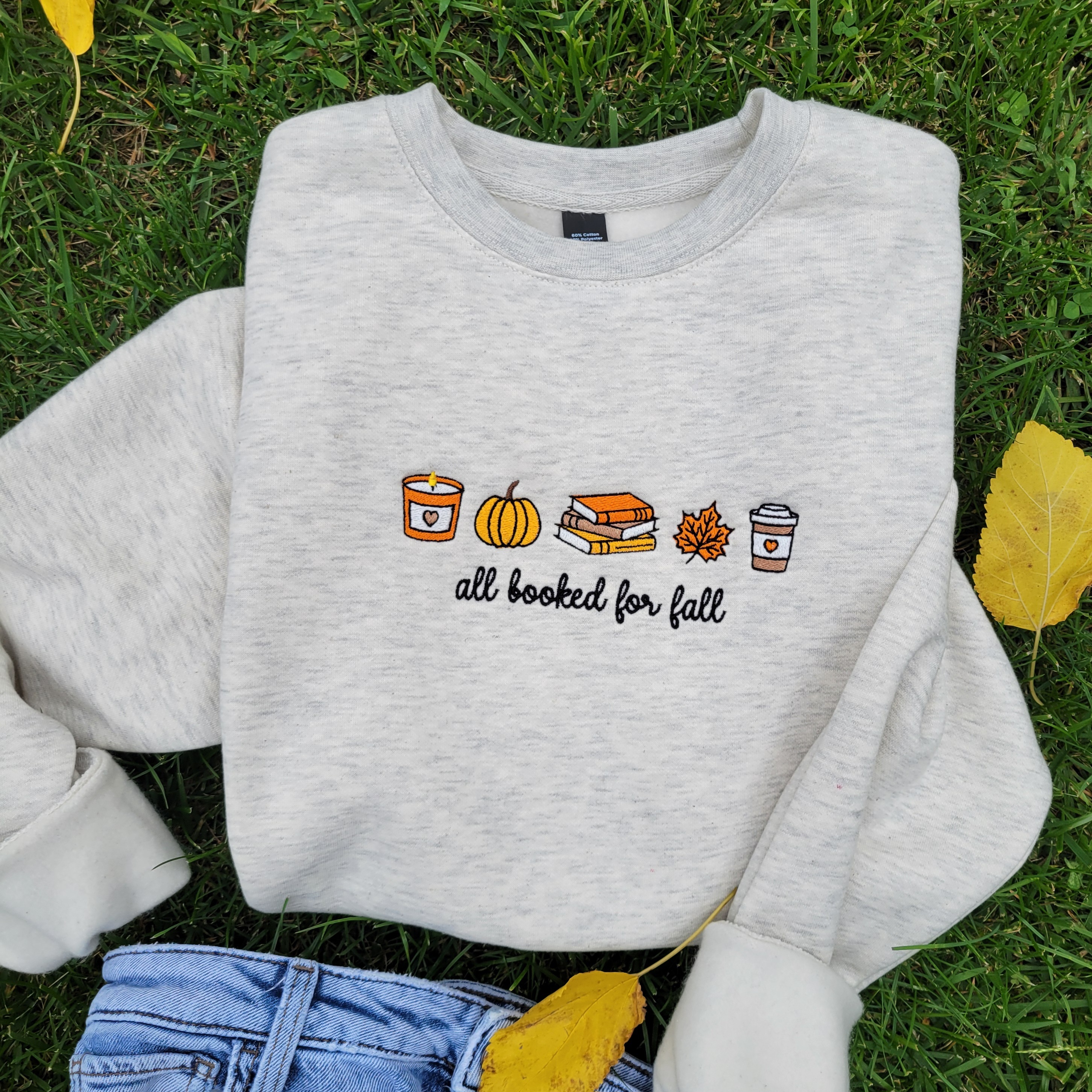 embroidered oatmeal colored crew neck sweatshirt with Fall seasonal embroidered of pumpkin, coffee and leaf in orange, brown.